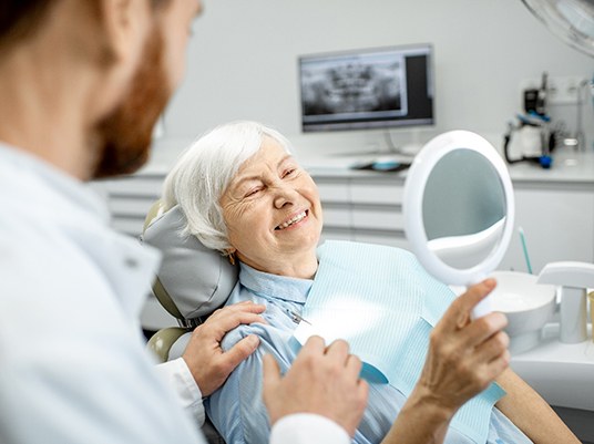 Woman in dental chair holding a mirror