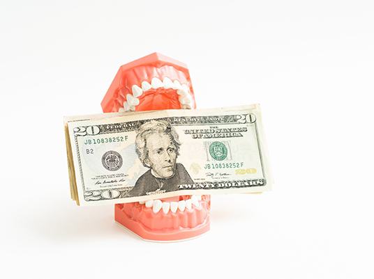 Dentures holding money representing the cost of dentures in Arlington 