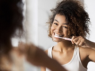 Woman preventing dental emergencies by brushing 