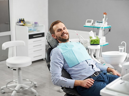 Male dental patient smiling and sitting back in dental chair
