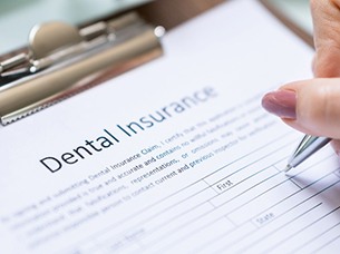 Filling out a dental insurance form on a clipboard