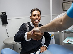 Young man shaking dentist’s hand after treatment