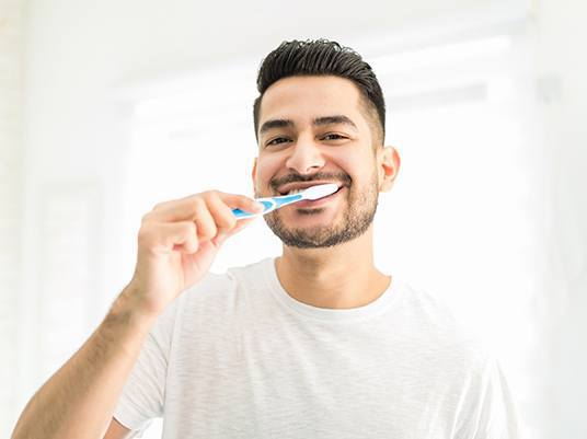 Man brushing his dental implants in Arlington 