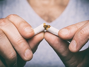 Closeup of patient breaking a cigarette for their dental implants in Arlington 