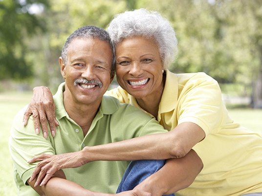 Couple with dental implants in Arlington smiling outside