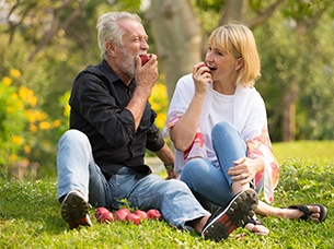 Couple with dental implants in Arlington eating apples outside