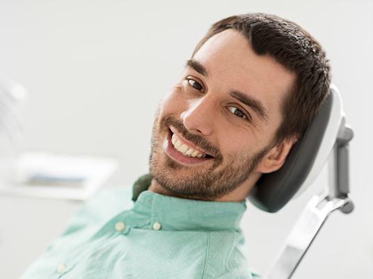 man laying back in exam chair smiling
