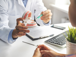 Dentist pointing to model of teeth in office