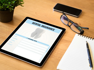 Dental insurance form on tablet next to desk supplies