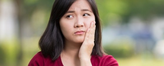 girl holding cheek in pain