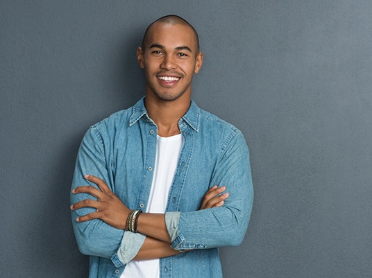 Man with arms crossed smiling in blue shirt