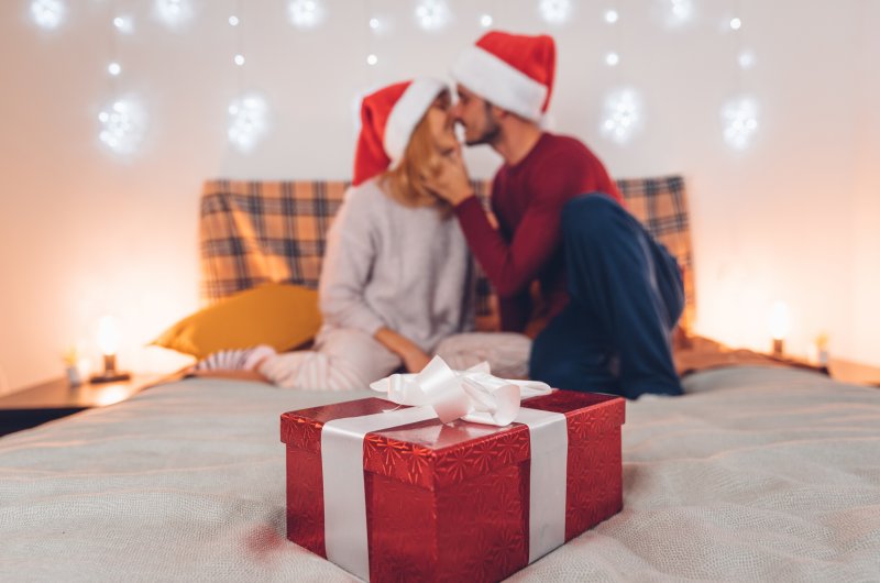 Closeup of present with couple touching noses in background